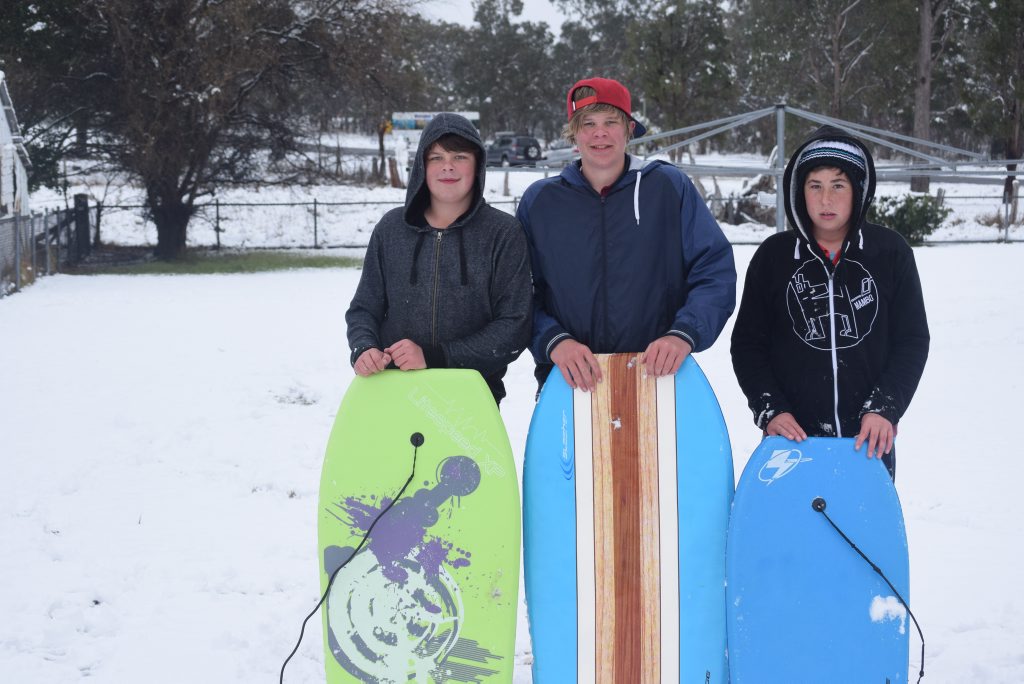 Kyle and James Garth with Hayden Riley 'boogie boarding' in the snow at Wallangarra. Photo: Alex Nolan / Stanthorpe Border Post